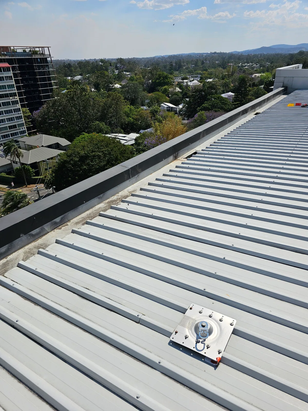 Wide inspection view across ribbed metal roof sheets and the perimeter edge