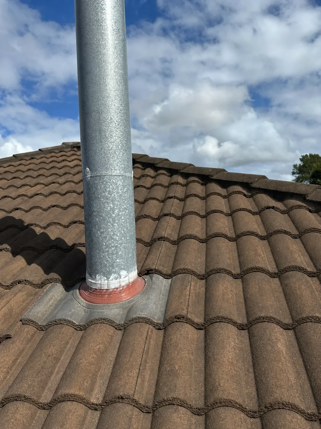Matching after view of the completed tile repair around a metal flue penetration