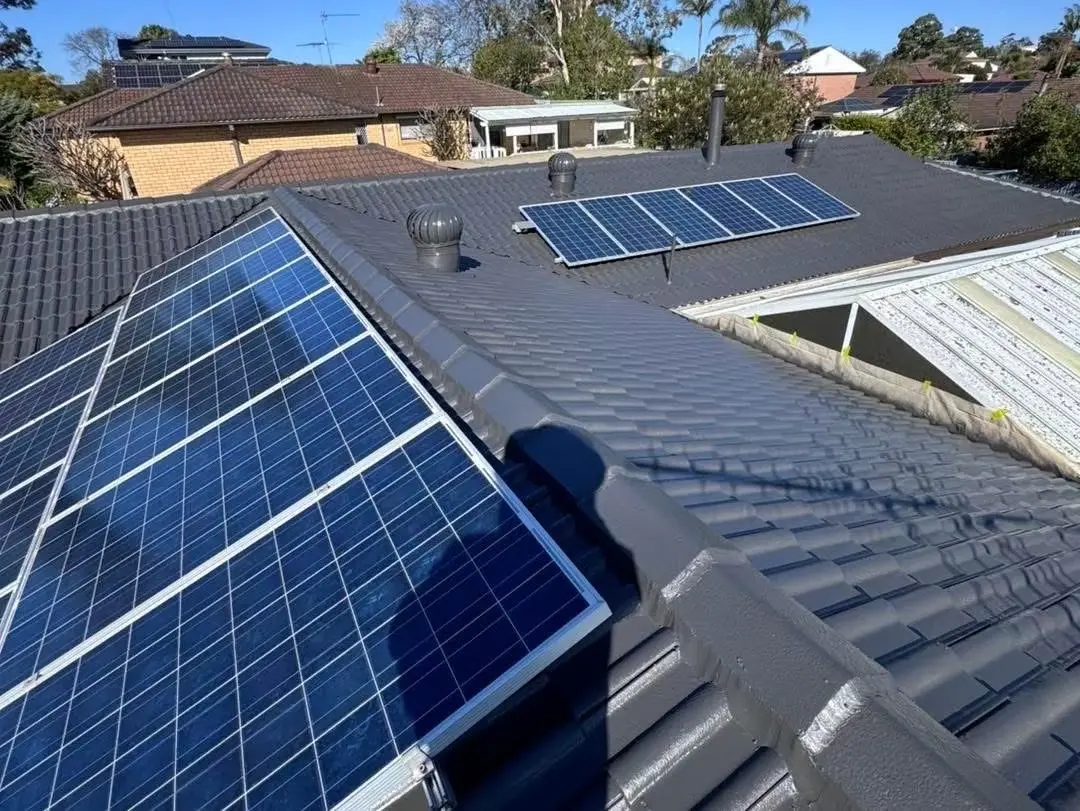 Completed dark-grey tile roof finish around existing solar panels